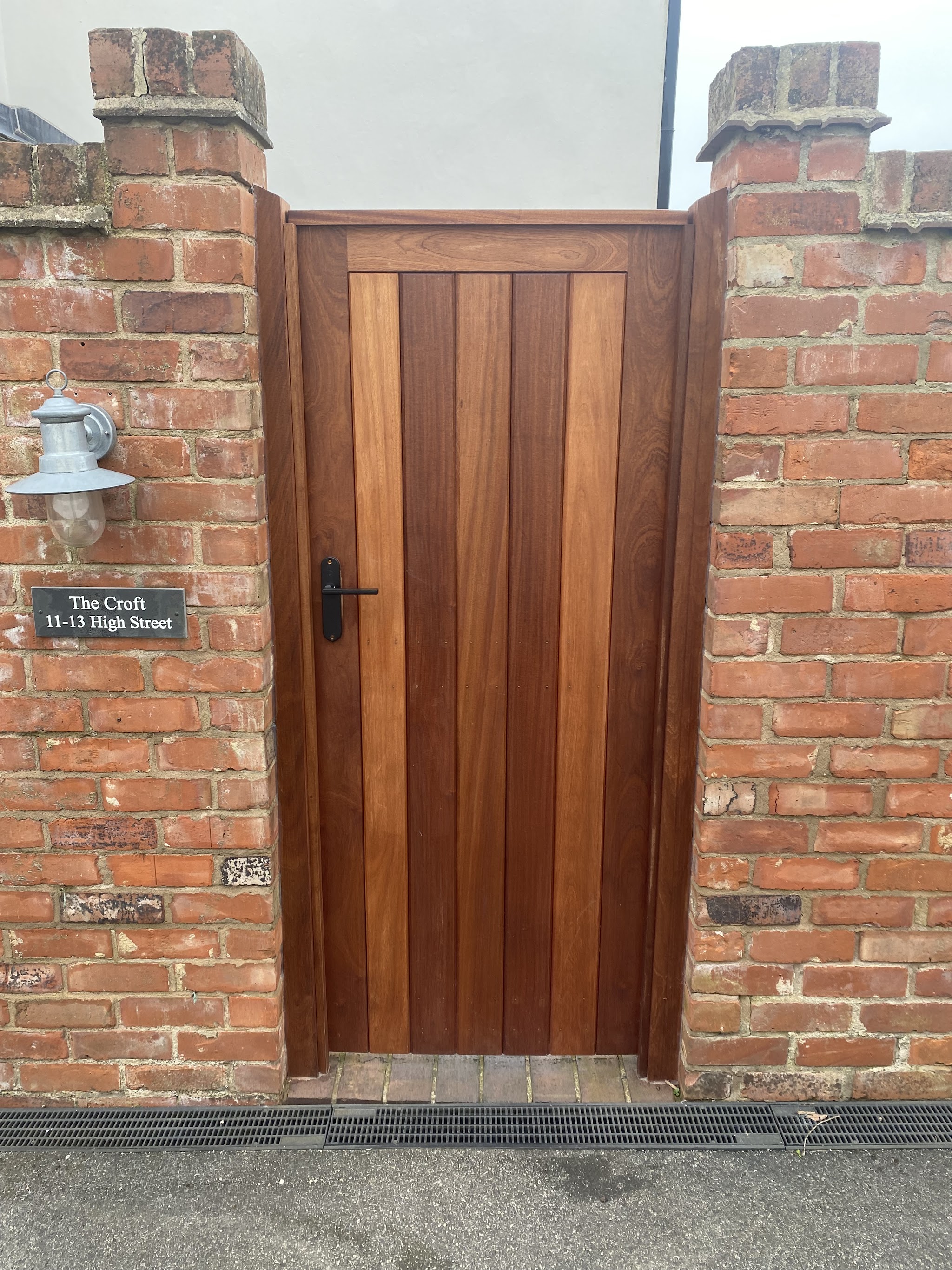 Hardwood ledged gate hung between two brick piers