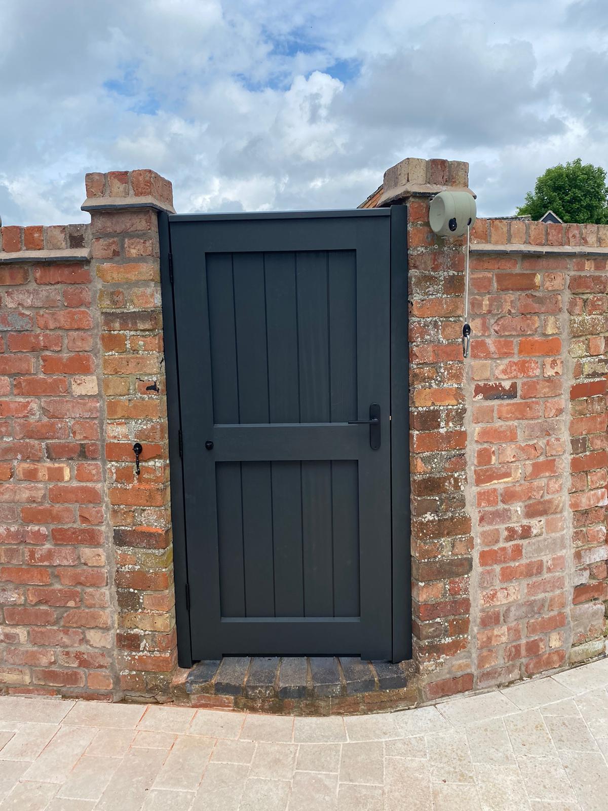 Dark painted ledged gate set into an old brick wall