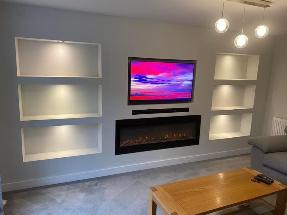 Media wall with lit alcove shelving and an inset fire