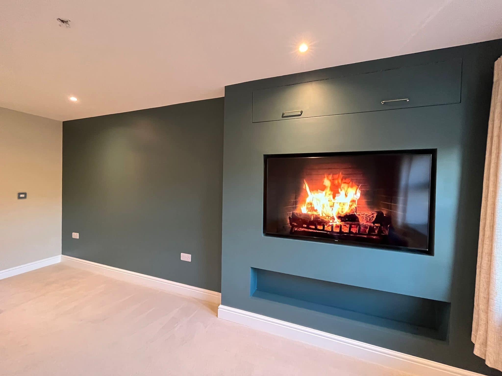 Dark green feature wall with a large inset fire and a recessed shelf below